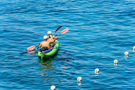 A man and a woman aboard a inflatable kayak, paddling in the blue Mediterranean sea, on a sunny summer day. Gulf of La Spezia, Liguria, Italy, southern Europe.の写真素材