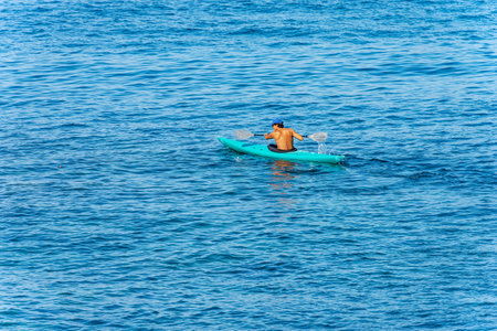 Young adult man, 30-35 years, paddle in the blue Mediterranean sea on a green kayak. Tellaro...