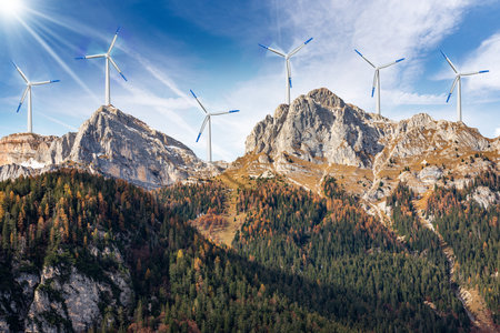 Group of white and blue wind turbines on the top of the mountain ridge, blue sky with clouds and...