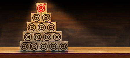 Stack of wooden blocks forming a pyramid, with many empty brown targets and one red one with an...