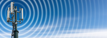 Closeup of a telecommunications tower with antennas (aerial) and radio waves, against a clear blue...