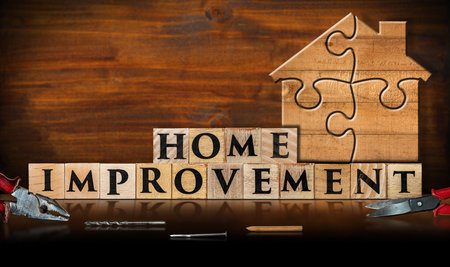 Wooden jigsaw puzzle pieces forming a house shape, on a wooden workbench with text Home Improvement made of wooden blocks. Home Improvement Concept.の写真素材