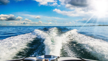 Close-up of the water wake of a speedboat or ship, view from the stern of the boat, sea view with blue sky and clouds on the horizon. Generative Ai.の素材