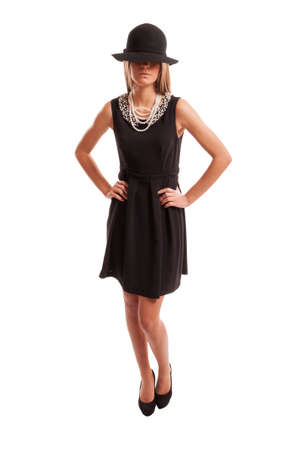 Female model standing and posing while wearing black dress and black hatの写真素材