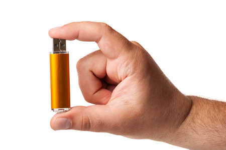 An USB memory stick hold between fingers isolated on a white backgroundの写真素材
