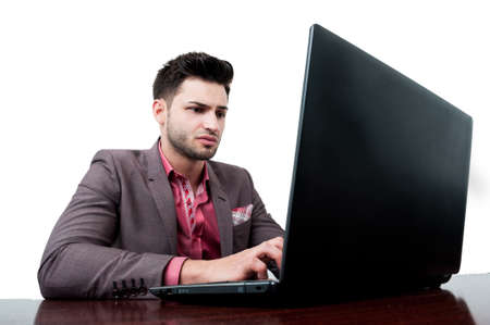 Serious business man with dark hair and beard typing on his laptopの写真素材