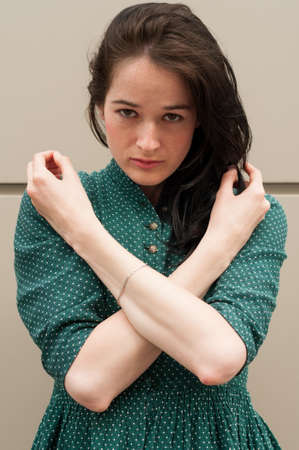 Beautiful girl with a natural look crossing her arms on the chest. She's wearing a green summer dress with white dots.の写真素材