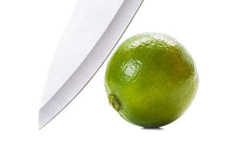 Steel knife and green lime on white backgroundの写真素材