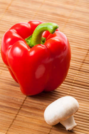 Red pepper and champignon mushroom on bamboo plateの写真素材