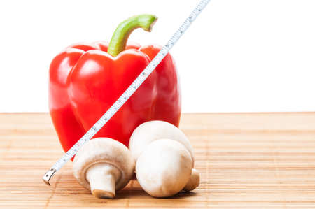 One red pepper, champignon mushrooms and a white measurement tapeの写真素材
