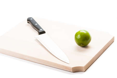 Big knife and green fresh lime on wooden board and white backgroundの写真素材