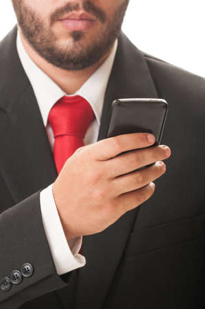 Business man checking his smartphone while wearing a classic black suit and red necktie.の写真素材