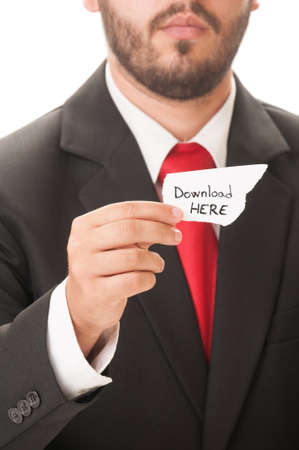 Download here concept using a man wearing a black suit and red necktie and holding a piece of paper with the text download here on it.の写真素材
