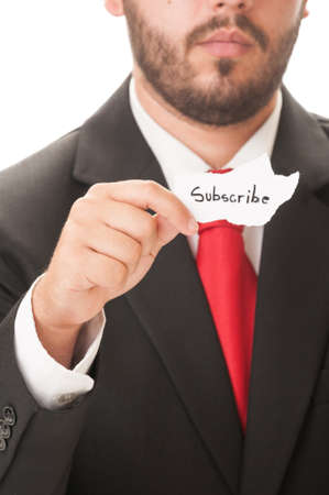 Subscribe concept using a man wearing a black suit and red necktie and holding a piece of paper with the text subscribe on it.の写真素材