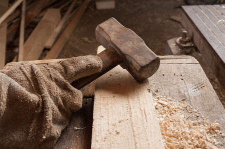 Worker hand with leather glove putting a hamer on  wooden tableの写真素材