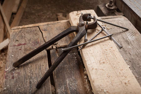 Old pliers and new nails on a carpenter's wooden tableの写真素材