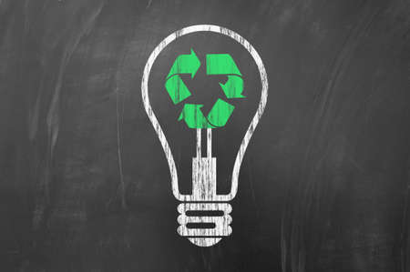 Recycling or saving electric energy concept using a light bulb and recycle symbol drawn on blackboard.の写真素材