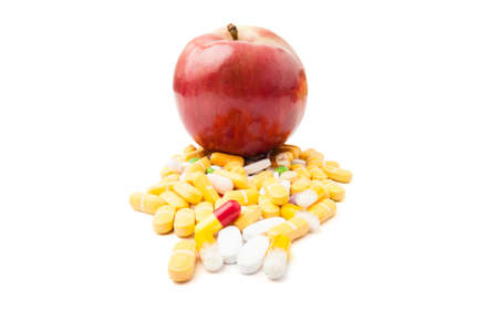 Perfect red apple on bunch of colored pills isolated on white backgroundの写真素材