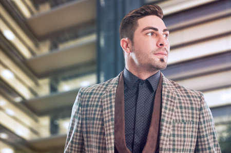 Confident and successful business man with company building as background