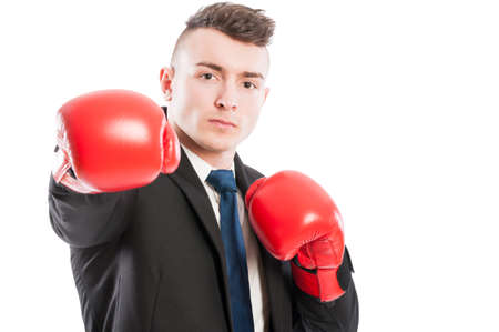 Confident business man wearing red boxing gloves punching the cameraの写真素材