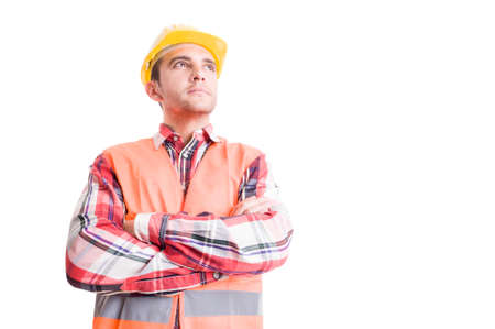 Confident builder with yellow helmet and orange vest looking up with arms crossed