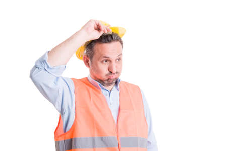 Shocked, tired or surprised worker or chef engineer lifting his yellow helmet