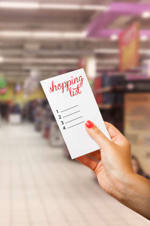 Woman hand holding shopping list in supermarket or hypermarketの写真素材