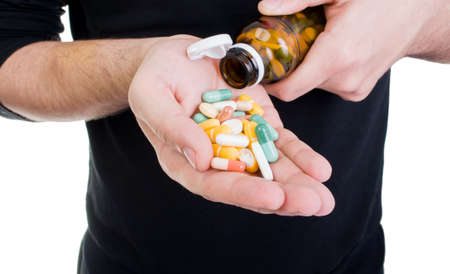 Man pouring many pills in hand from bottleの写真素材