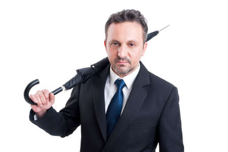 Confident and serios business man holding closed umbrella on his shoulderの写真素材