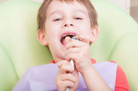 Kid having fun in dental office playing with air blower