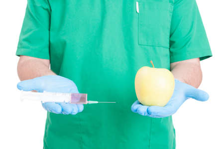 Medic or doctor hands holding a syringe and an apple on white backgroundの写真素材