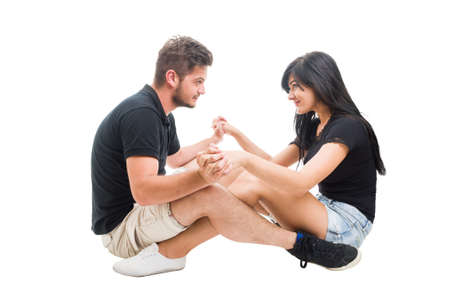 Young happy couple sitting and facing each other while holding hands as lovers on a date