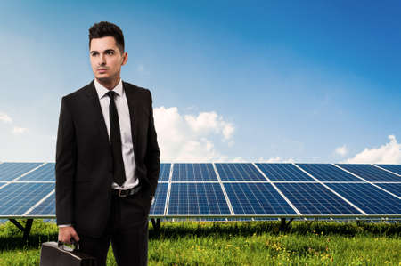 Salesman or businessman holding briefcase on solar power panels background. Manager of sun energy companyの写真素材