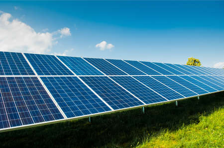 Solar power panels on green field with blue sky and copy space and text area