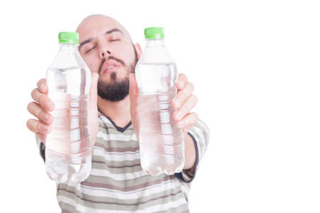 Thirsty man holding two bottles of cold water as hydration or dehydration in summer heat conceptの写真素材
