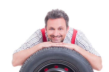 Friendly mechanic resting head on tire isolated on whiteの写真素材