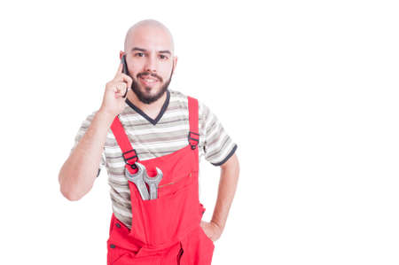 Young  mechanic talking on the phone looking happy into the camera isolated on whiteの写真素材