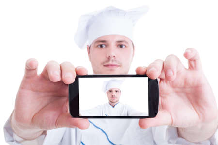 Chef or cook taking selfie with back phone camera showing his face on the screen or displayの写真素材
