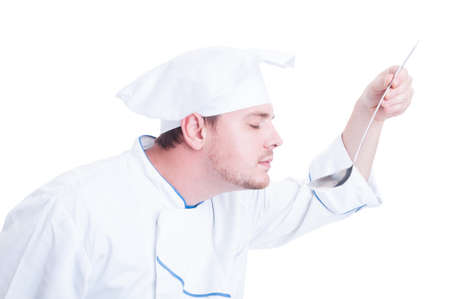 Chef or cook smelling flavor soup from ladle isolated on whiteの写真素材