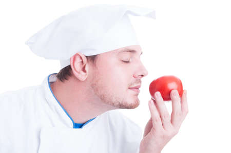 Cook or chef smelling small fresh organic perfect red tomato isolated on white backgroundの写真素材