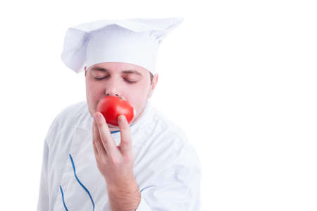 Cook or chef smelling fresh organic perfect red tomato isolated on whiteの写真素材
