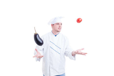 Chef or cook juggling with vegetables an eggpland and one tomato isolated on white studio backgroundの写真素材