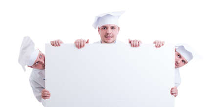 Three cooks or chefs holding a blank cardboard with white copy space for advertising. Professional cook or chef holding big menu board conceptの写真素材