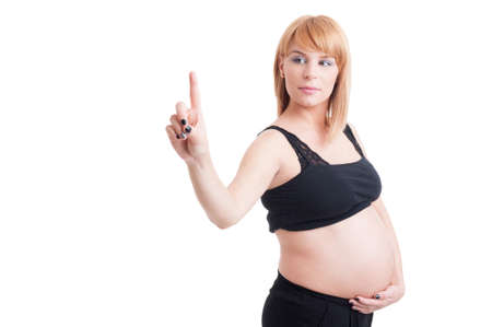 Young attractive pregnant woman poiting or pressing finger on invisible screen with copy space and blank white advertising areaの写真素材