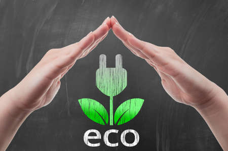 Hand protecting green energy concept draw on blackboard or school chalkboard