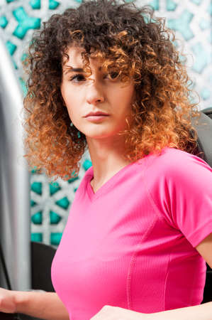 Beautiful female model with curly hair posing in the gym