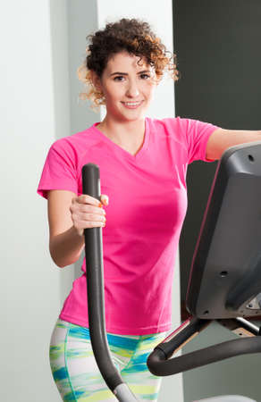 Attractive woman smiling during the stepper workout exercises in the gym