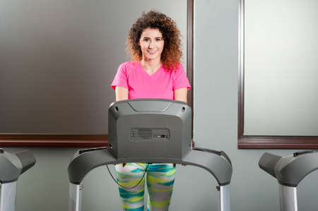 Beautiful female smiling and exercising on treadmill in the gym