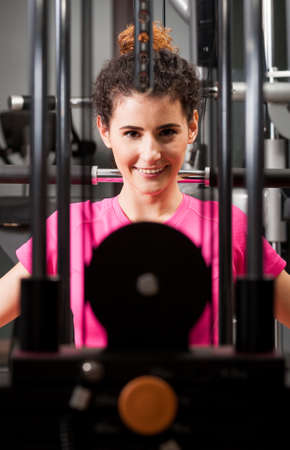 Attractive female face thru gym equipment smiling and exercising as sporty lifestyle