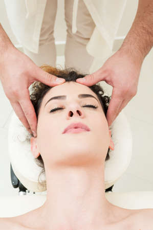 Attractive female having a forehead or head massage at spa by male masseur